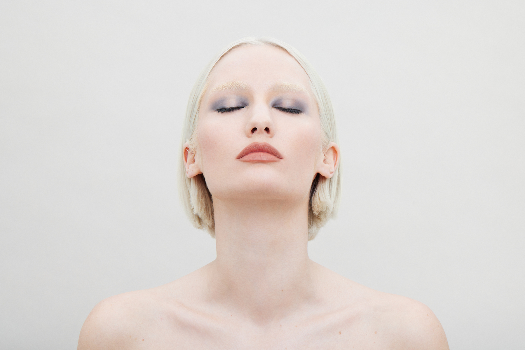 Beauty campaign portrait for Ecoglo Cosmetics featuring a platinum-blonde model with smoky eye makeup and nude lipstick, photographed in Miami by Josh Eskridge.