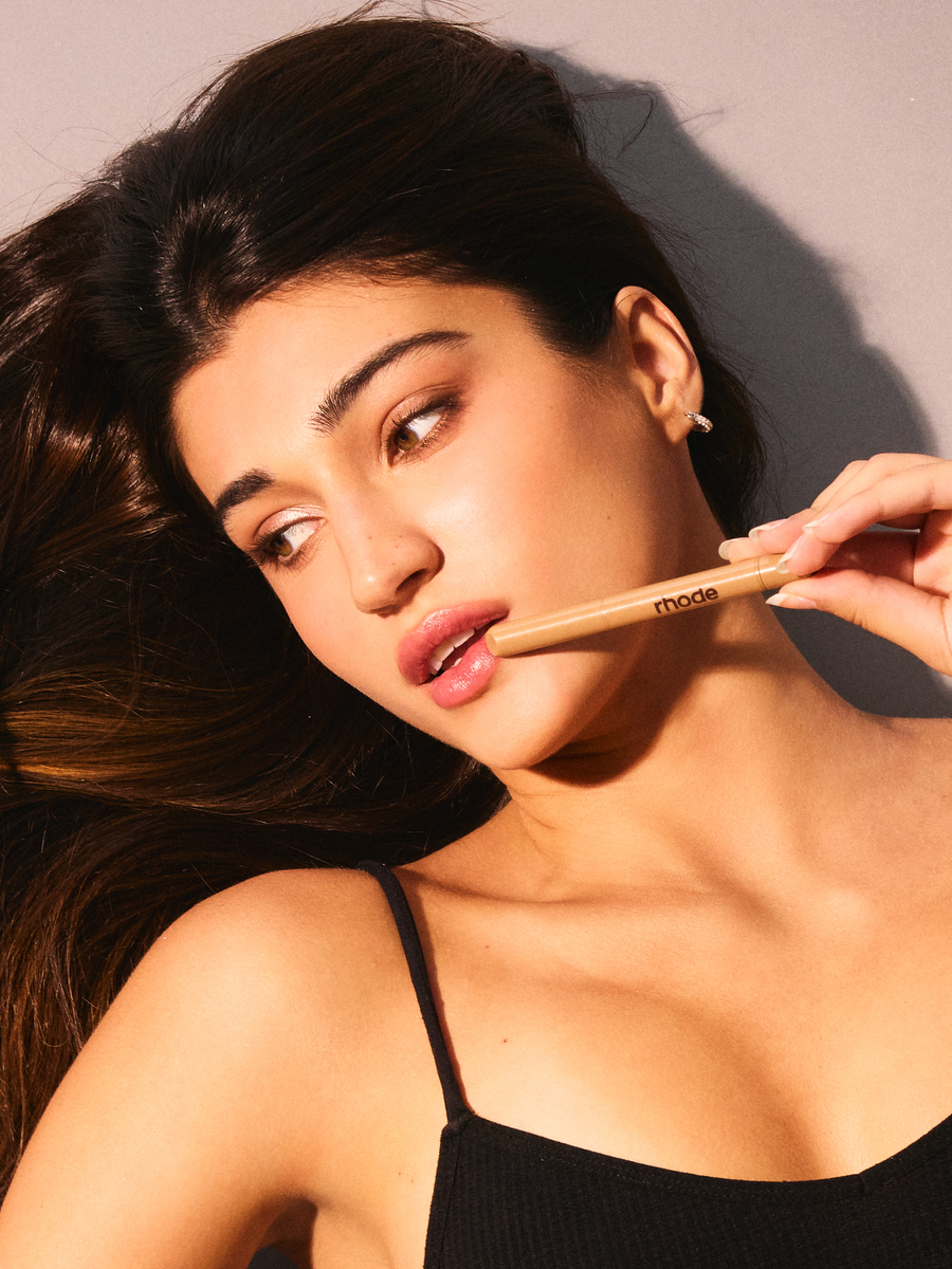 Model Rachel Carillo holding a Rhode beauty product near her glossy lips during a spec shoot at Know Good Studio in Miami.