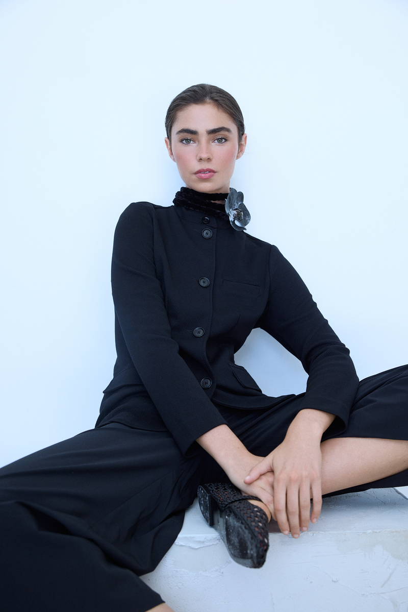 Editorial fashion portrait of a brunette model wearing a structured black jacket with a black floral accent, photographed at Know Good Studio in Miami by Josh Eskridge.