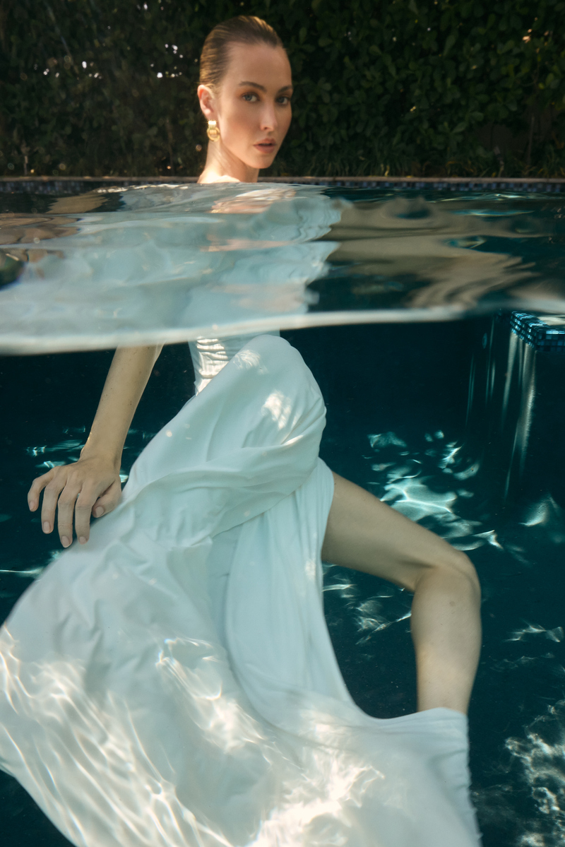 Underwater fashion portrait by Josh Eskridge of a model wearing a flowing white designer dress in a swimming pool, photographed for Heiress Beverly Hills in Miami.