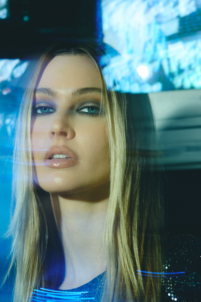 Editorial beauty portrait of model Laken Romine with glossy makeup and blue cinematic reflections, photographed at the vintage TV wall inside Know Good Studio in Miami by Josh Eskridge