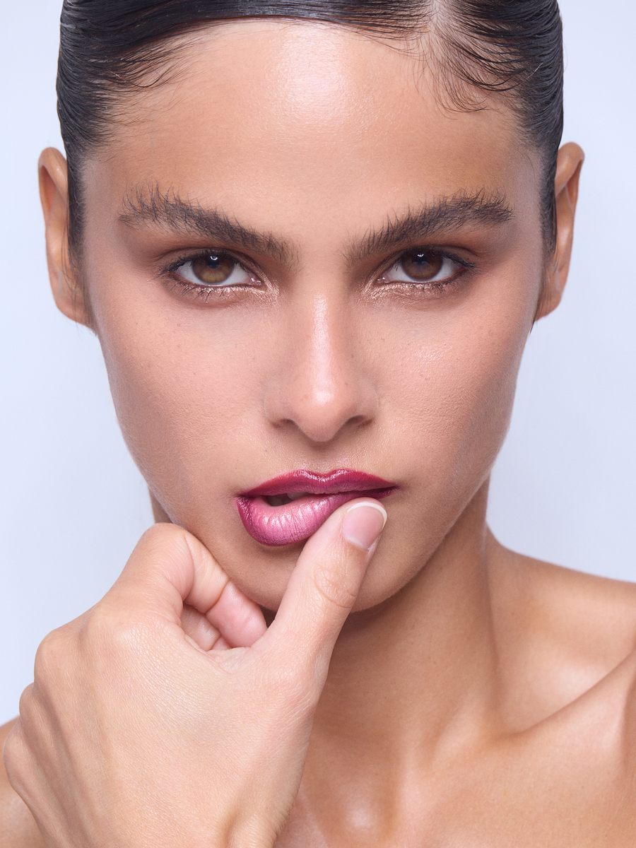 Close-up beauty portrait of a model wearing metallic berry-pink lipstick, softly defined eyes, and sleek hair, photographed in Miami by Josh Eskridge.